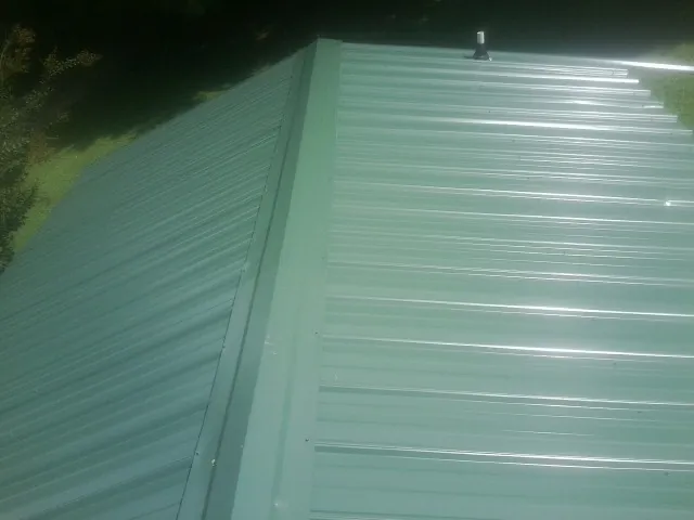 New green metal panels meeting at the ridge of a roof — Flat Roof Repair work by our crew in Dry Branch