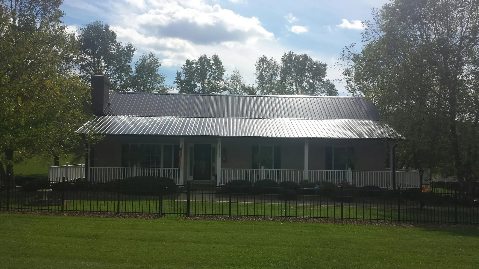 Gray metal roof on a brick ranch with a full width front porch — Gutter Guard Installation work by our crew in Dry Branch