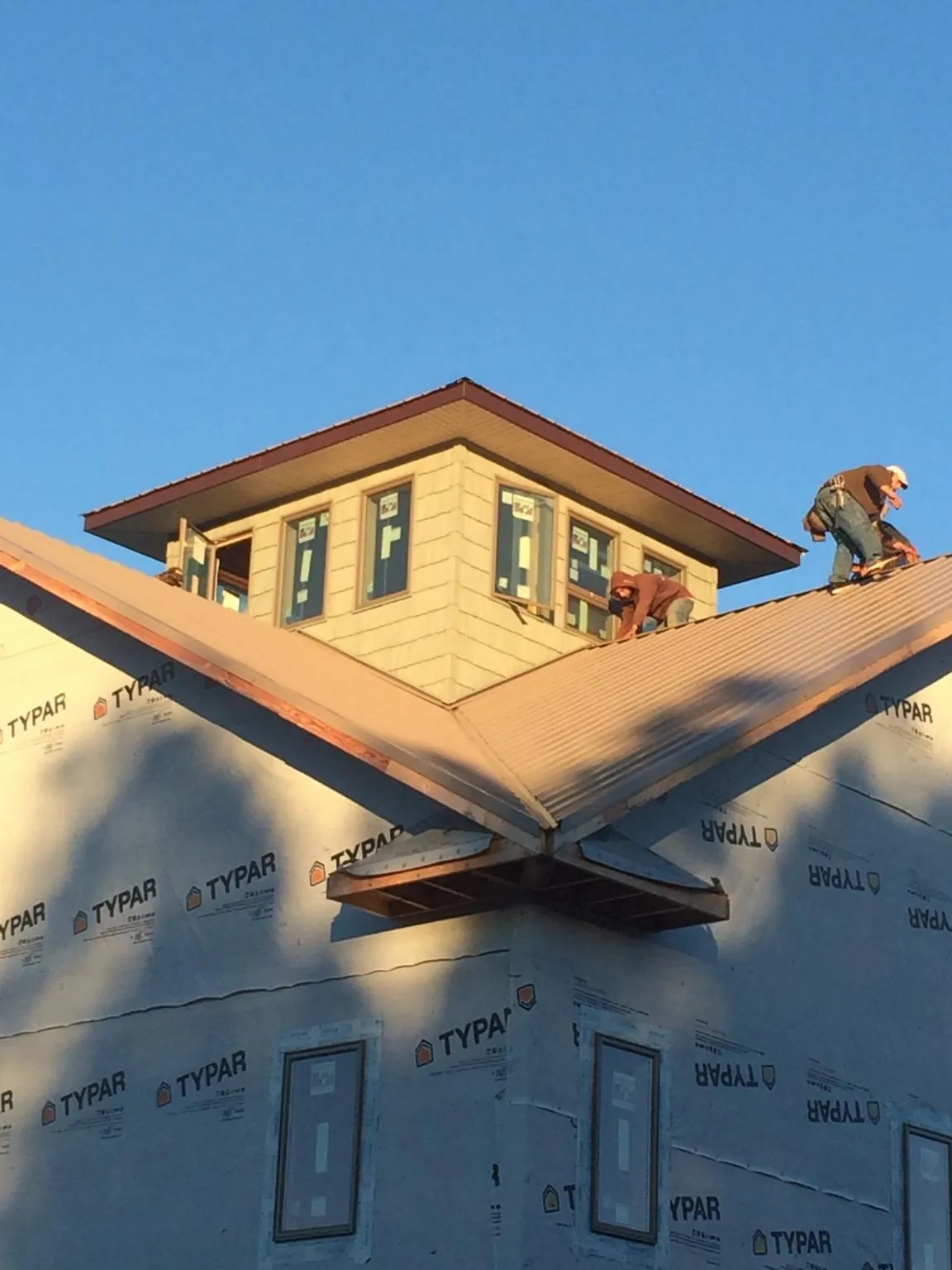 Roofers working around a rooftop cupola on a new metal roof at sunset — Roof Waterproofing in Dry Branch by Roofing Brothers